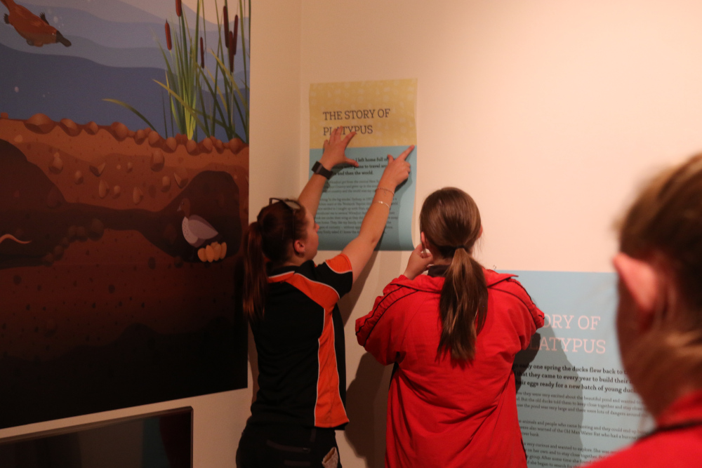 Installing a decal onto the wall under direction from a junior curator